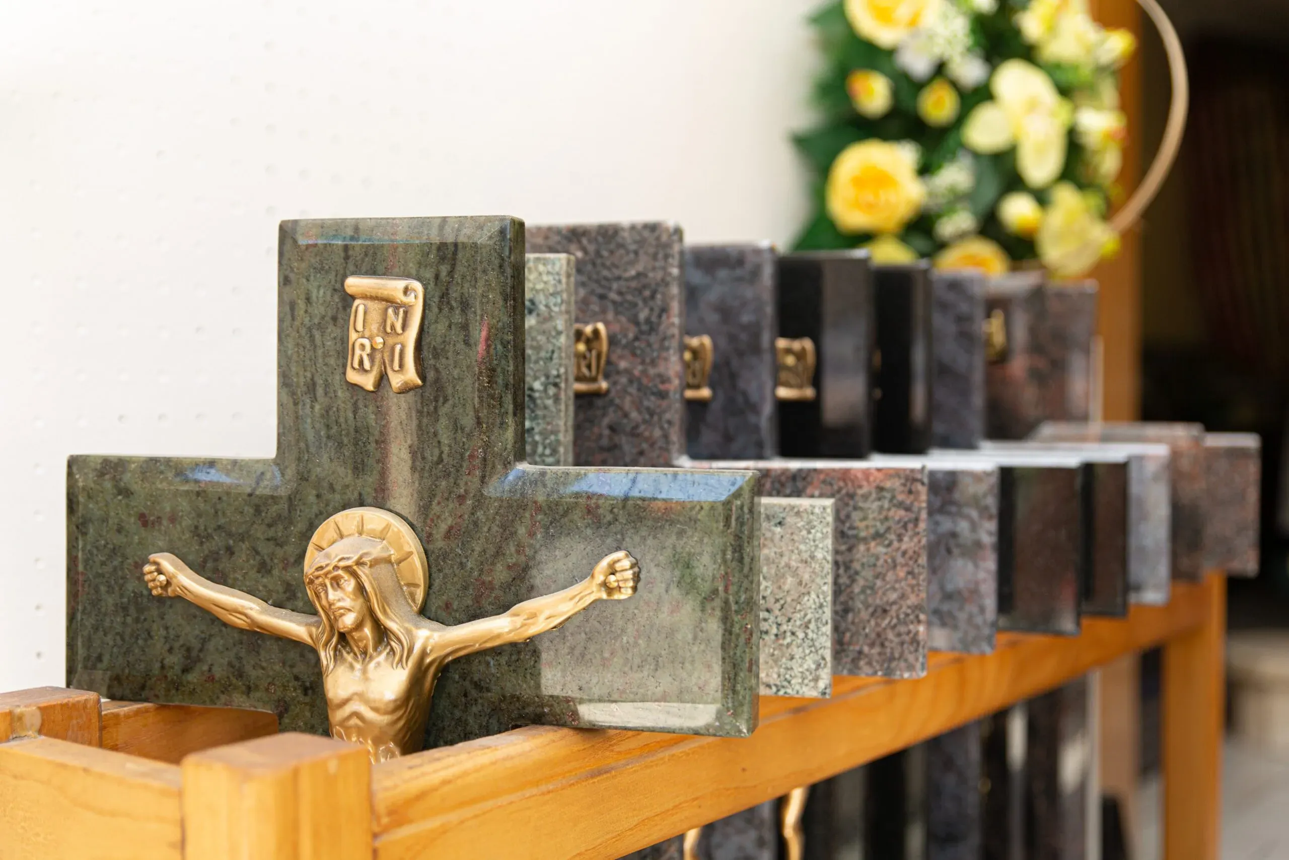 Croix funéraire en pierre avec Christ en bronze présentée en magasin.