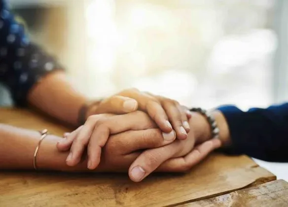 Geste de réconfort et de soutien par des mains enlacées pendant un deuil.